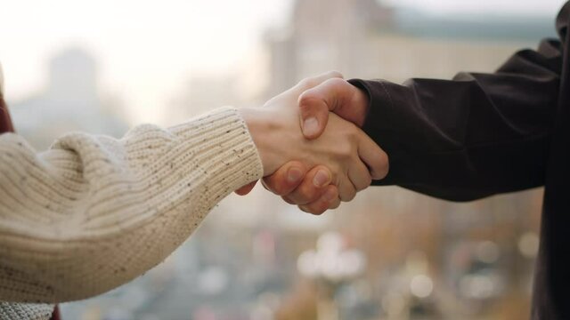 Closeup man and woman hands greeting. Unknown couple shaking hands outdoors.