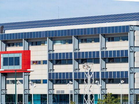 Fachada de edificio publico con placas solares fotovoltaicas en el tejado.