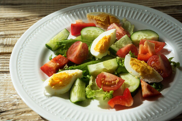 rustic summer salad with fresh cucumbers, tomatoes and eggs on a white plate. the view from the top