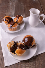 Freshly baked cupcakes drenched in hot chocolate and jug of milk in the background, soft focus.