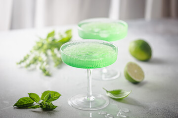 Summer green cocktail with lime, basil and ice in a crystal glass