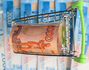 Russian money in a small cart on a background of money.
