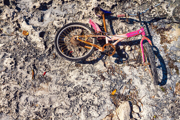 Rusty pink bicycle lying on stones of ocean coast in Zanzibar