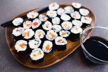 plant-based food, vegan sushi with seaweed and sticky rice with capsicum on serving tray next to bowl with soy sauce