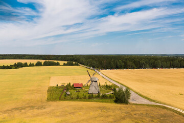 Small windmill in the field in belorusian village, view from helicopter. Wheat field in bright sunlight.