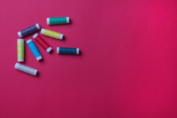 group of spool of threads on red colored paper background, with copy space