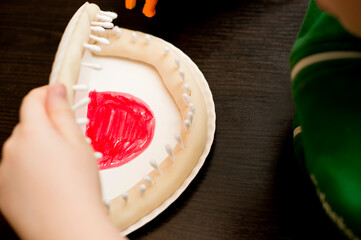 DIY play oral hygiene. boy making mouth with teeth from paper plate and ear buds. reminding Carnivorous Plant.