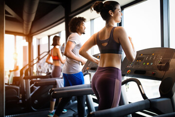 Young people running on a treadmill in modern gym