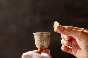 Pray with holding loaf and little cup of the wine.