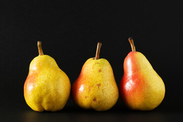 Fototapeta na wymiar Three ripe williams pears on black background.
