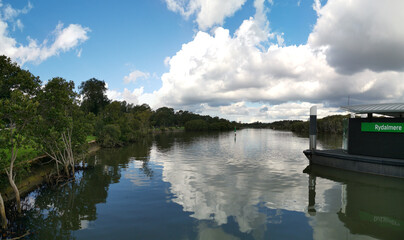 Obraz premium beautiful early morning view of river with reflections of blue sky, clouds and trees on water, Rydalmere Wharf, Parramatta river, Rydalmere, New South Wales, Australia