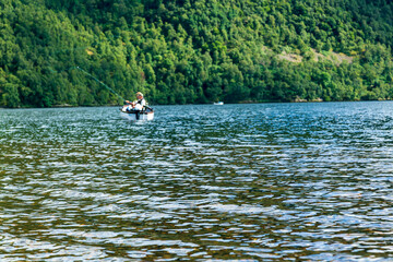 湖の水面のアップと遠くの方でボートに乗り釣りをする人たち