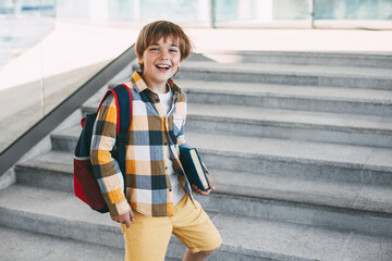 Happy boy with a backpack and a book goes to school. Beginning of the new school year after the summer holidays. Back to school
