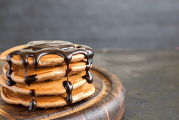 Chocolate pancakes with chocolate syrup on a dark background.