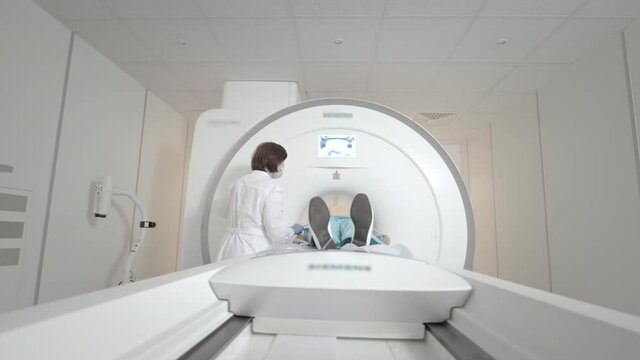 The doctor performs an MRI scan for a patient at the clinic. The girl lies in the MRI device. Magnetic resonance imaging in the study of the human body. Modern technologies in medicine.