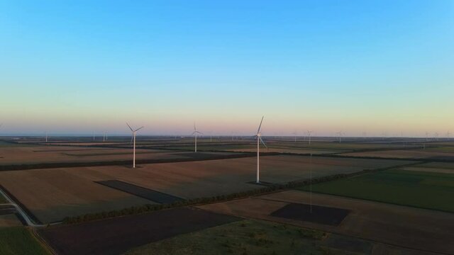 Cinematically smoothly revealing a huge wind turbine park on sunset near Shabla, Bulgaria