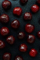 Bright ripe black cherry on a black background. Drops of water on the cherry.