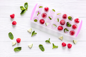 Naklejka na ściany i meble Ice tray with berries, lime and mint on white background top view