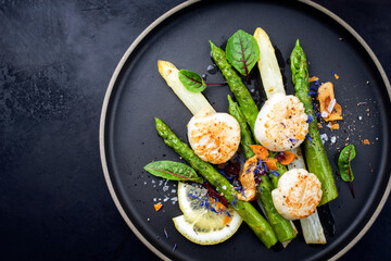 Traditional barbecue scallops with green and white asparagus offered as top view on a modern design...