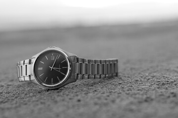 The watch is put on the sand Natural light blurry background (Vintage black and white image concept)