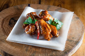 Appetizing fried chicken wings in sauce on a wooden tray. The concept of food and serving, food in bars and restaurants