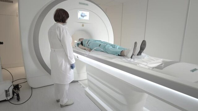 The doctor performs an MRI scan for a patient at the clinic. The girl lies in the MRI device. Magnetic resonance imaging in the study of the human body. Modern technologies in medicine.