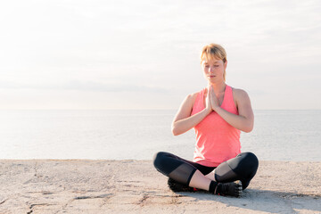 Fototapeta na wymiar woman practicing yoga sitting in front of the sea