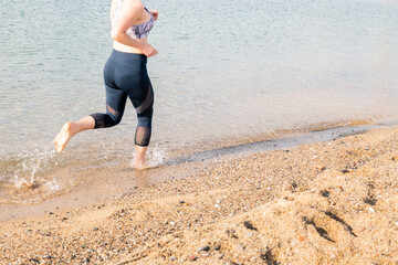 unrecognizable sportswoman running along the beach