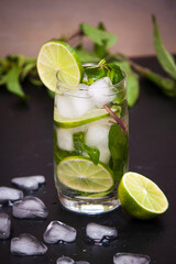 Summer coctail mojito with ice, mint, lime on a grey background. Copy space.