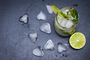 Summer coctail mojito with ice, mint, lime on a grey background. Copy space.