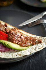 Various culinary dishes on a dark wooden table. Exquisite restaurant serve on dark dishes