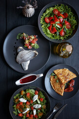 Various culinary dishes on a dark wooden table. Exquisite restaurant serve on dark dishes