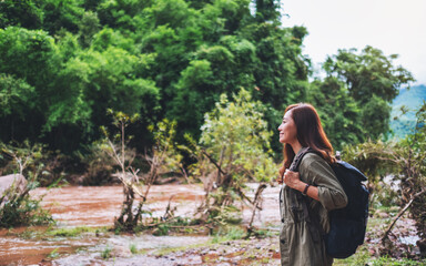 A female traveler with backpack walking  by mountain stream for hiking concept