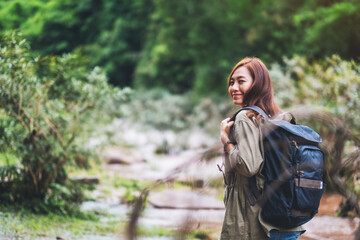 A female traveler with backpack walking  by mountain stream for hiking concept