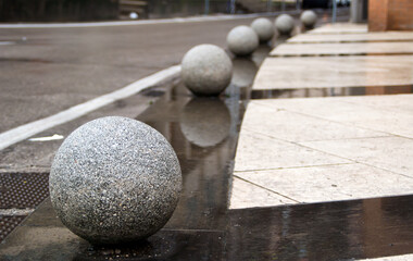 granite balls on an empty wet pavement on a rainy day