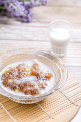 Thai dessert concept. Tapioca pearls form sago three with coconut milk, corn and young coconut in transparent bowl on wooden table.