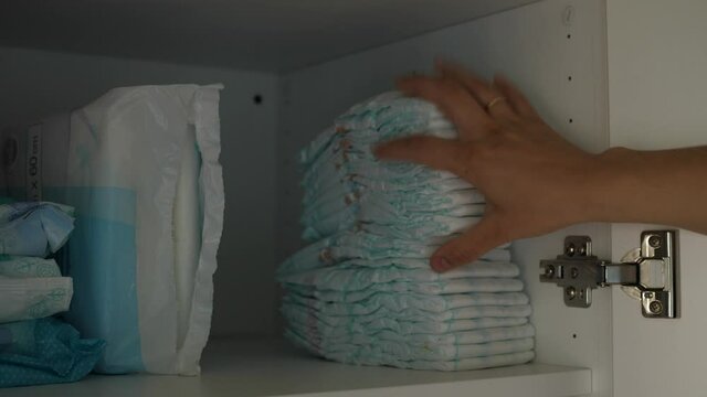 hands putting disposable diaper in cupboard