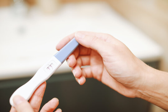 Female hand holding positive white plastic pregnancy test with two stripes.Picture of a pregnancy test with pregnant results.