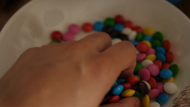children's hands take colorful dragees candies chocolate