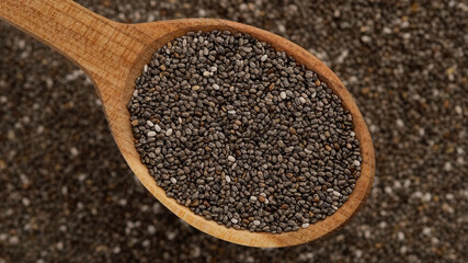 chia seeds in wooden spoon and on background