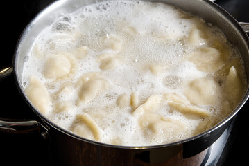 cooking dumplings in a pan with water, Meat in dough rolls. Top view.