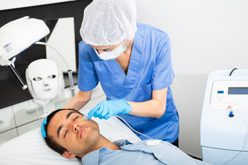 Young man client getting carboxy therapy on face skin, cosmetology beauty treatment at esthetic...