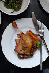 Homemade confit duck leg served with sweet potatoes and padron pappers