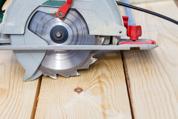Close-up of a metal blade with teeth of an electric hand saw on a background of fresh yellow wooden...