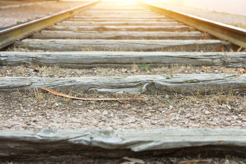 Empty old railroad track with weathered wood planks in perspective golden sunlight on horizon low...