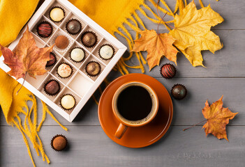 Naklejka na ściany i meble Hot coffee or tea drink in a cup a box of chocolates on a background of autumn. Copy space Top view flat layout.
