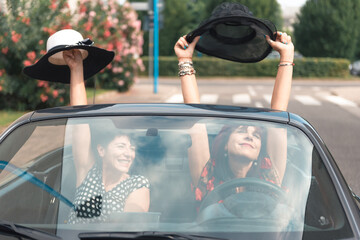 Amiche donne alla guida di un'auto convertibile godendo le vacanze divertendosi sulla strada.