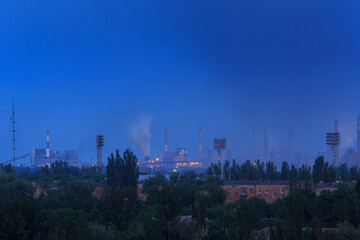 Panorama of a large metallurgical plant that smokes heavily on the outskirts of the city in the evening