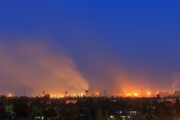 Fototapeta premium Panorama of a large metallurgical plant that smokes heavily on the outskirts of the city in the evening