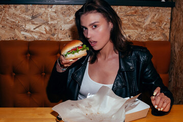 Hungry Young Fashion Lady Eating a Hamburger in a Cafe